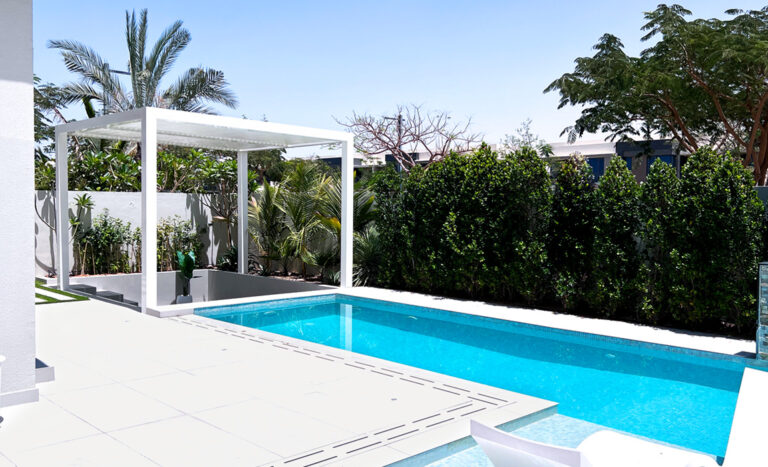 Villa pool with a white pergola and hedge screening at Villa 174, Dubai Hills